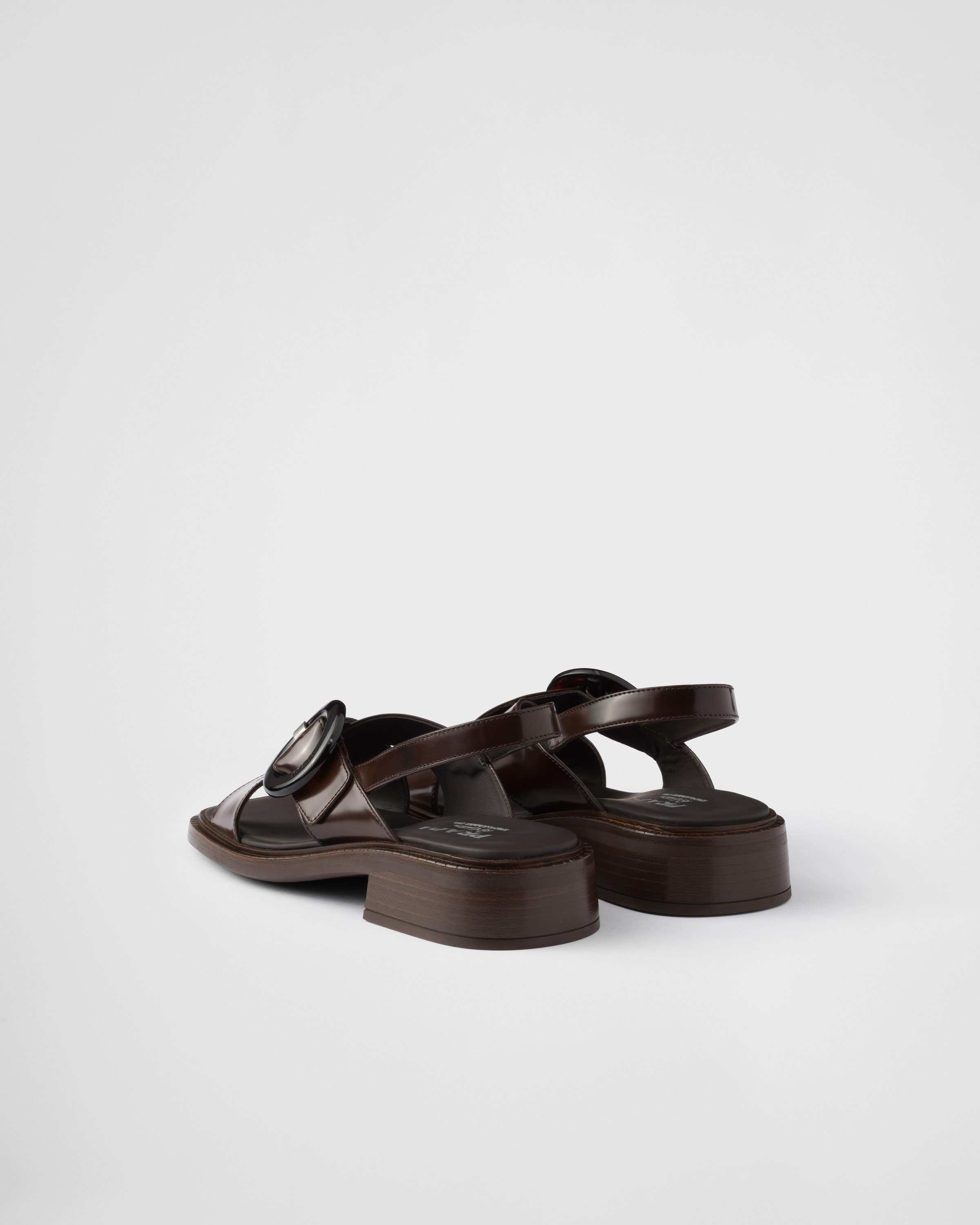 Prada Brushed Leather Crisscross Band Sandals With Plexiglas Buckle In Sienna
