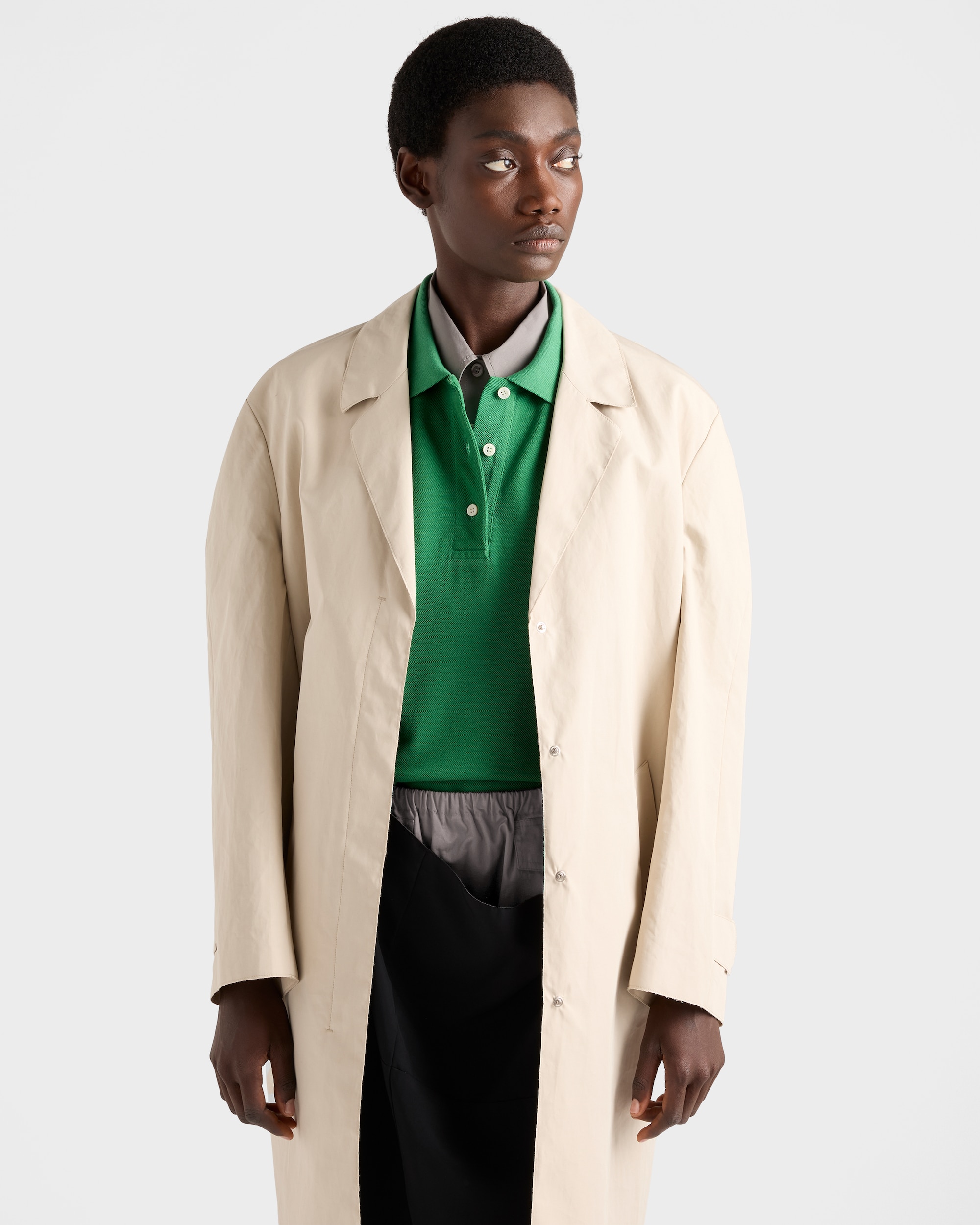 Model wearing green piqué polo shirt under a beige coat.