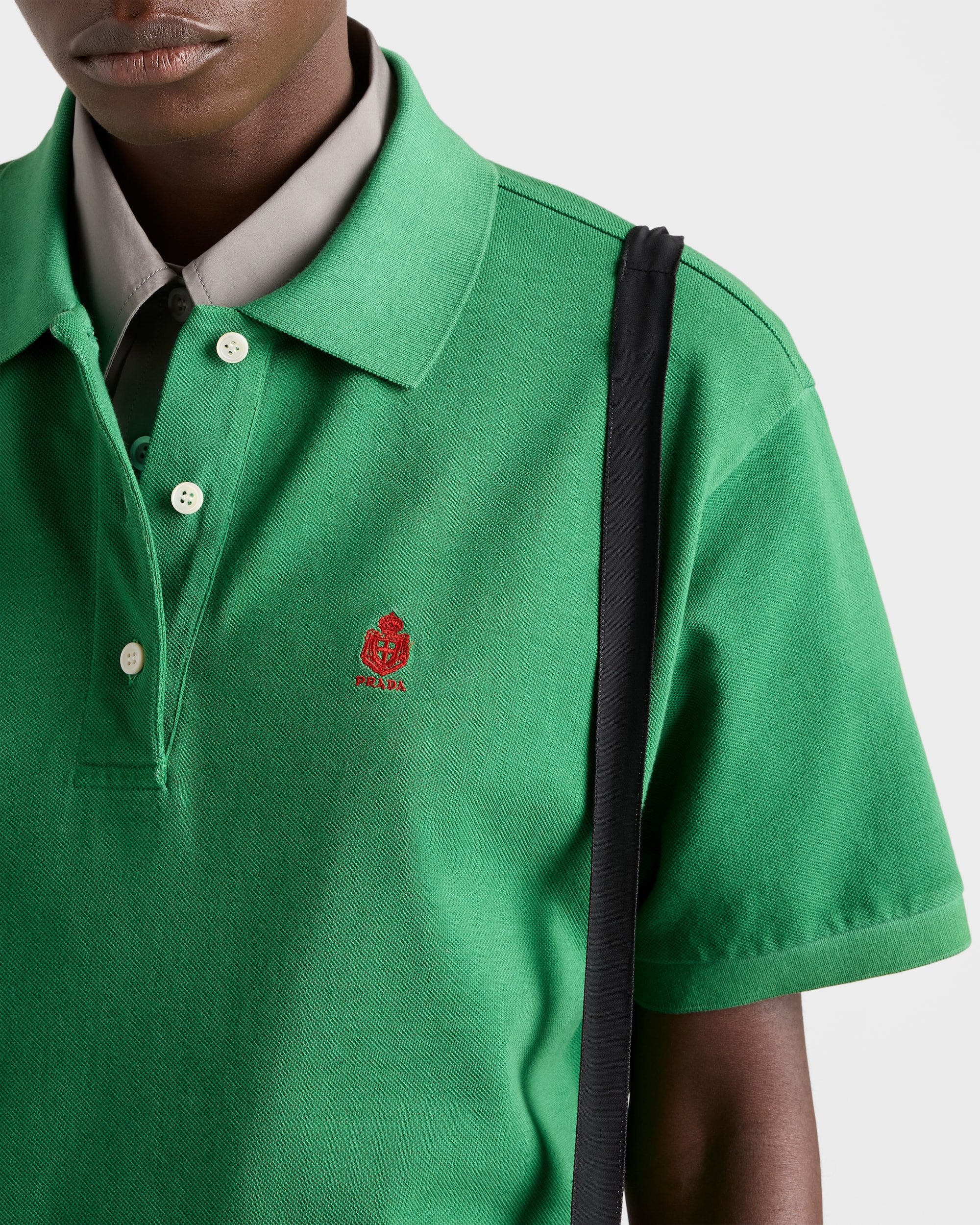 Close-up of green polo collar, buttons, and embroidered crest logo.