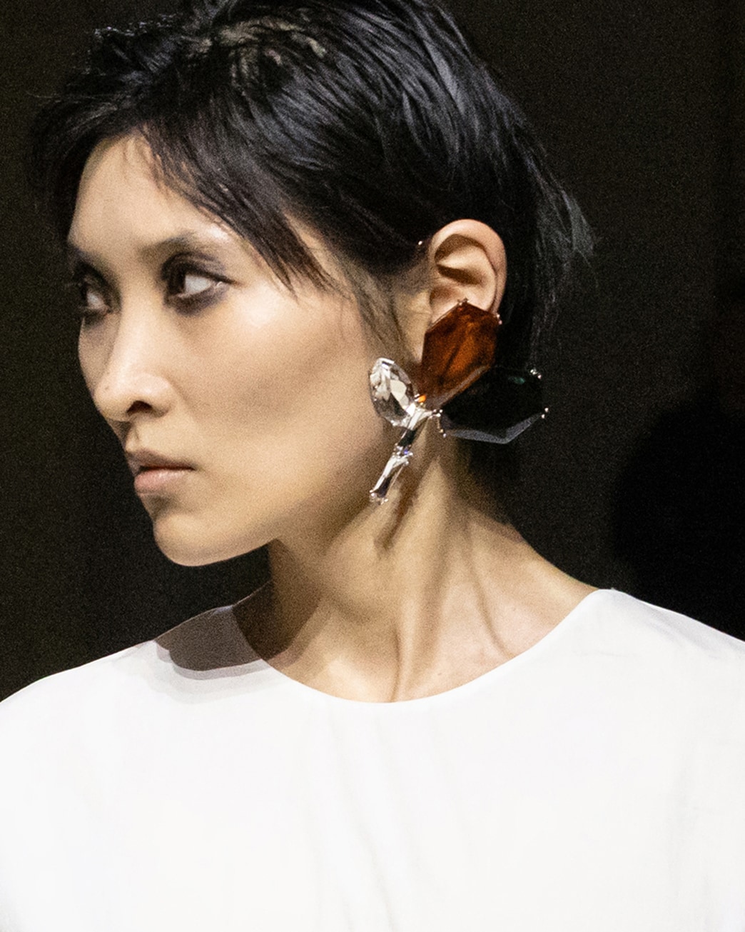 프라다 FW26 뷰티 디테일. 짙은 눈매, 자연스러운 입술, 큰 귀걸이